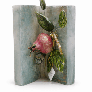 Κέρινο βιβλίο με κεραμικό ρόδι και φύλλα σε γκρι απόχρωση.